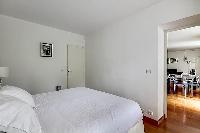 cozy bedroom with a king-size bed and large, custom-fitted wardrobes in a 1-bedroom Paris luxury apa