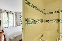 en-suite bathroom with a bathtub and a handheld shower head in a 1-bedroom Paris luxury apartment