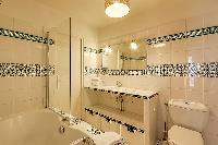 en-suite bathroom with a bathtub and a handheld shower head in a 1-bedroom Paris luxury apartment