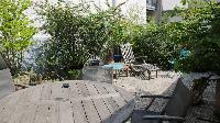 big terrace with potted plants and flowers, coffeetable and chairs in a 1-bedroom Paris luxury apart