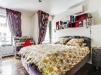 cozy bedroom with a queen-size bed, plenty of storage space and a TV in a 1-bedroom Paris luxury apa