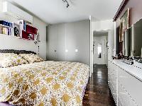 cozy bedroom with a queen-size bed, plenty of storage space and a TV in a 1-bedroom Paris luxury apa