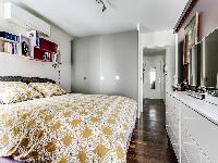 cozy bedroom with a queen-size bed, plenty of storage space and a TV in a 1-bedroom Paris luxury apa