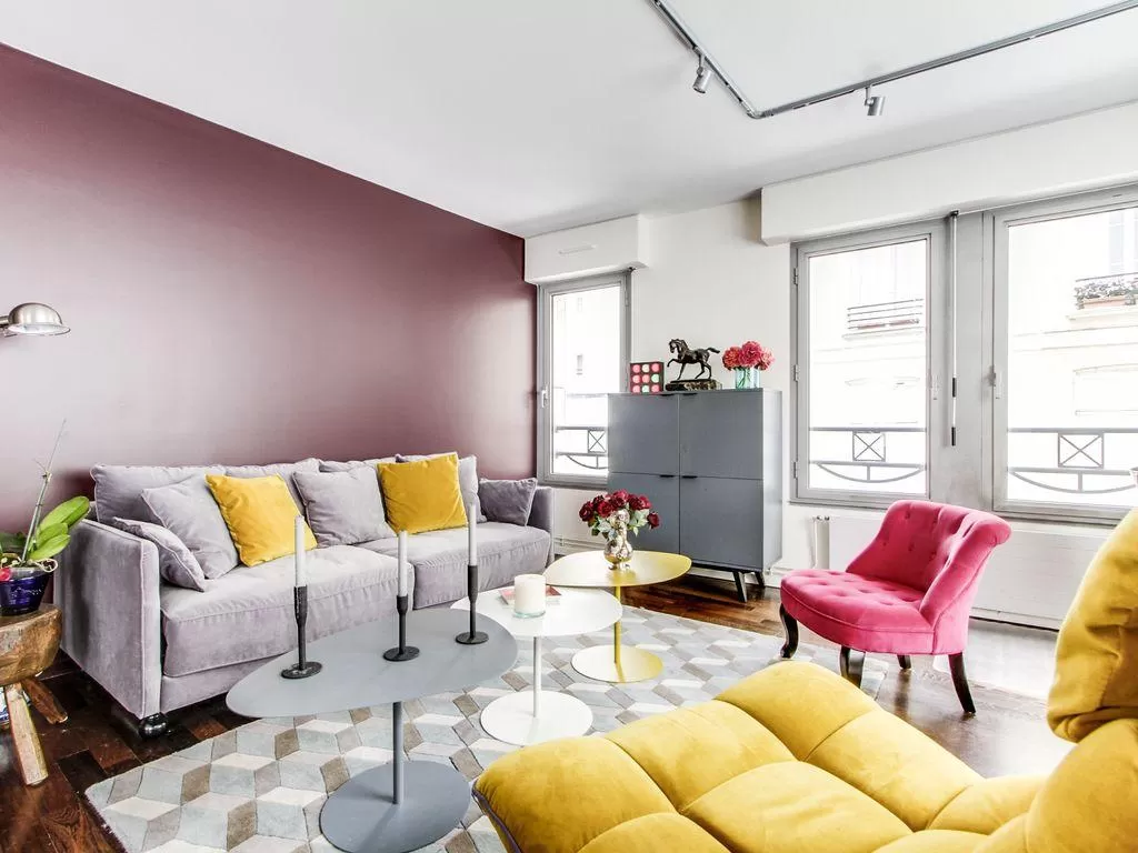 living room in yellow and rose hues with a double sized sofa-bed and three antique pianos in a 1-bed