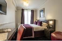 double bed, wooden study desk, and purple draped window in Hotel Waldorf Madeleine in Paris