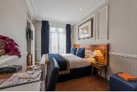 double bed, wooden study desk, and royal blue draped window in Hotel Waldorf Madeleine in Paris