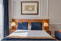 double bed, wooden study desk, and royal blue draped window in Hotel Waldorf Madeleine in Paris