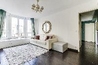 elegant open plan living with white sofa, furry cream carpet rug and gree draped windows in Paris lu