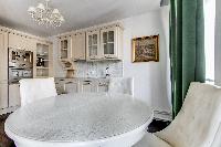 elegant open plan living and dining area with white dining table and chairs, fully equipped kitchen,