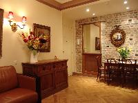 stylish brick-walled dining area with wooden table and chairs, wooden cabinets, and brown leather so