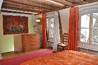 warm and bright master bedroom with two twin beds or a king size bed, red carpet rug, cabinet, red a