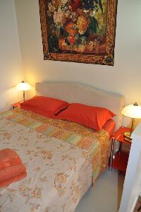 second bedroom with a queen size bed and a glass paned door leading to the terrace with a parasol, t