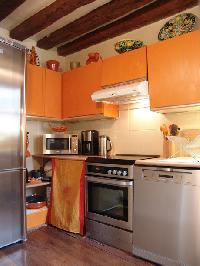 fully-equipped kitchen in tangerine hue and exposed beams in a 2-bedroom Triplex Paris apartment