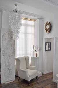 elegant white armchair beside a framed artwork and stylish chandelier in Paris luxury apartment