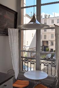 round coffee table for 2 beneath a ceiling lamp overlooking the courtyard in Paris luxury apartment