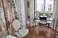 classy bedroom with elegant white armchair and framed artwork in Paris luxury apartment