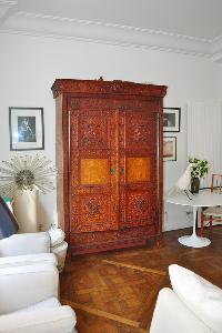 spacious, bright and airy living area with white sofas and antique wooden cabinet in Paris luxury ap