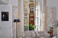 elegant white armchair beside a framed artwork beneath a stylish chandelier in Paris luxury apartmen
