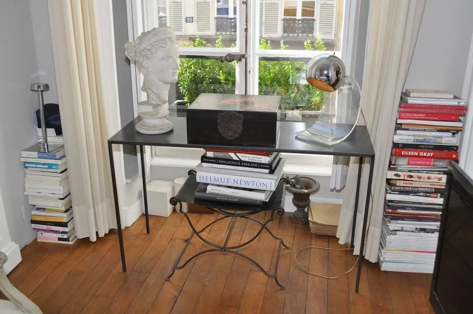 glass study desk, bust, and tower of books in Paris luxury apartment