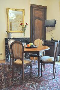 wooden round table for 4, elegant chandelier, and ornamental fireplace beneath elaborate mirror in P