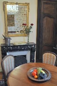 wooden round table for 4, elegant chandelier, and ornamental fireplace beneath elaborate mirror in P