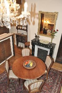 wooden round table for 4, elegant chandelier, and ornamental fireplace beneath elaborate mirror in P