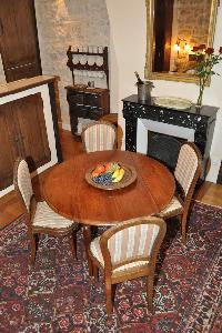 wooden round table for 4, elegant chandelier, and ornamental fireplace beneath elaborate mirror in P