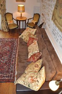 brown long sofa with floral throw pillows and armchairs with nightstand and lamp in Paris luxury apa