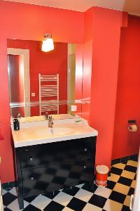 sleek bathroom with black-and-white tiles and red wall in Paris luxury apartment