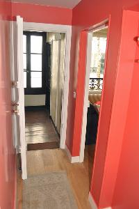 hallway with red walls and beautifully lined parquet floors in Paris luxury apartment