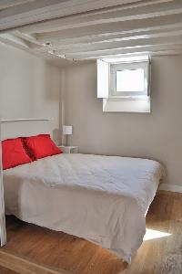 queen size bed and exposed beam in Paris luxury apartment