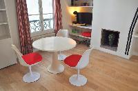 dining area with white round table and red chairs in Paris luxury apartment