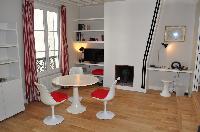 dining area with white round table and red chairs in Paris luxury apartment