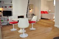 dining area with white round table and red chairs in Paris luxury apartment