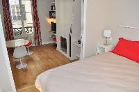 neatly stocked bedroom separated by a sliding door from the living room in Paris luxury apartment