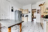 well-equipped kitchen with dining table and chairs in a 4-bedroom Paris luxury apartment