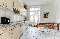 well-equipped kitchen with dining table and chairs in a 4-bedroom Paris luxury apartment