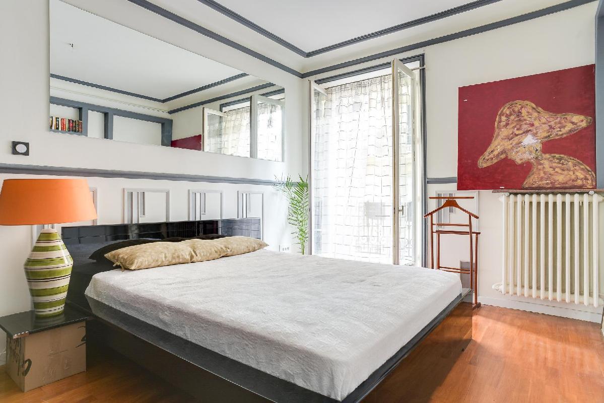 master bedroom with a queen size bed and access to the small balcony via a large floor to ceiling wi