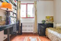 second bedroom with a single bed, lamp, desk and collection of books in a Paris luxury apartment