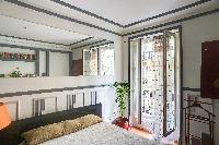 a large window that leads to a small balcony with street view in a  2-bedroom Paris luxury apartment