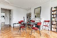 spacious dining area with 4 seats, mirror, ornamental fireplace and book shelves in a 3-bedroom Pari