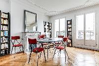 spacious dining area with 4 seats, bright windows and book shelves in a 3-bedroom Paris luxury apart