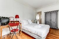 bedroom with queen size bed, TV, and studydesk and chair in a 3-bedroom Paris luxury apartment