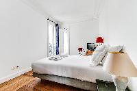 bedroom with queen size bed, TV, and studydesk and chair in a 3-bedroom Paris luxury apartment