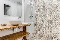 A separate modern bathroom with sink and shower in a 3-bedroom Paris luxury apartment