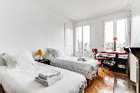 bedroom with two single beds, study desk, shelves, and ornamental fireplace in a 3-bedroom Paris lux