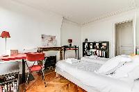 bedroom with two single beds, study desk, shelves, and ornamental fireplace in a 3-bedroom Paris lux