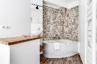 an en suite bathroom with sink, handheld shower and a gorgeous bathtub in a 3-bedroom Paris luxury a