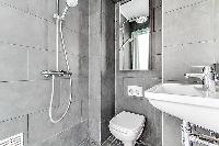 a slate grey and white full bathroom with both handheld and rain shower, toilet and sink in a charmi