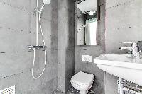 a slate grey and white full bathroom with both handheld and rain shower, toilet and sink in a charmi